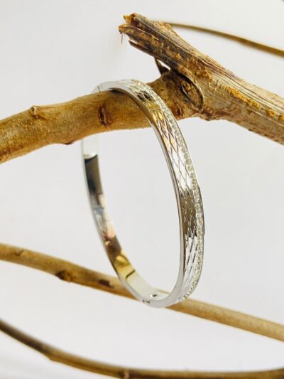 Sleek silver bangle with diamond-cut texture and elegant stone detailing